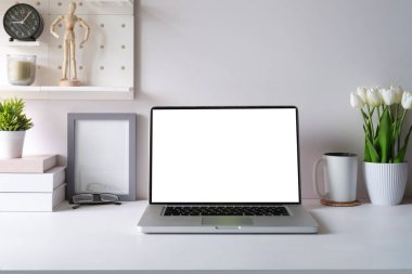 Front view laptop, alarm clock, books and potted plant on white office desk. Creative workplace.	