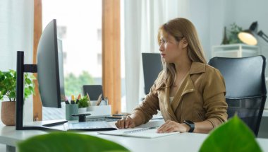 Modern cihazlarla ev ofisinde yaratıcı proje üzerinde çalışan güzel genç bir kadın..