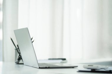 Yan görünüm dizüstü bilgisayar, hesap makinesi, belge ve defter ve beyaz ofis masası.