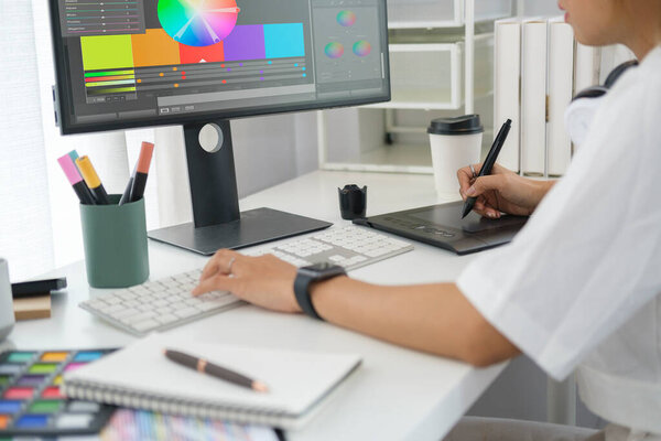 Cropped shot of young creative woman using graphics tablet and a stylus pen at creative office.