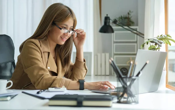微笑的女人在她的办公室里用笔记本电脑创业 — 图库照片