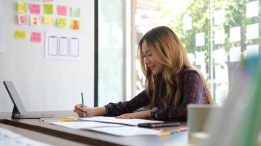 Smiling female graphic designer working with new startup project in modern office.	