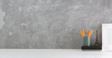 Blank poster frame on white table with cement wall.Copy space for products display montage.	