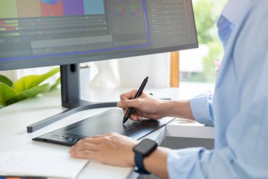 Yaratıcı adamın grafiksel tablet kullanarak modern ofiste yeni bir proje üzerinde çalışırken çekilmiş görüntüleri..