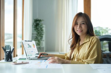 Dizüstü bilgisayar kullanan başarılı girişimci ve parlak modern ofiste muhasebe belgesi ile çalışıyor.