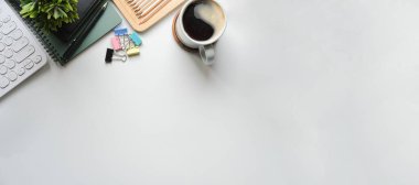 Not defteri, kahve fincanı ve klavyesi olan beyaz masa. Metnin için boşluk kopyala.