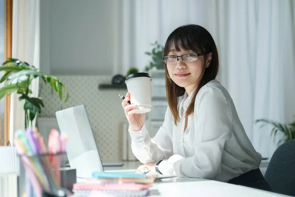 魅力的な若いアジアの女性はコーヒーを飲み 明るい現代オフィスで働く — ストック写真