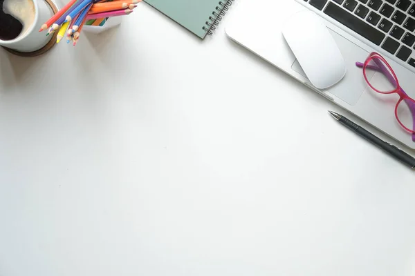 Düz dizüstü bilgisayar, gözlük, kahve fincanı ve kırtasiye malzemesi beyaz masada duruyordu. Metnin için boşluk kopyala.