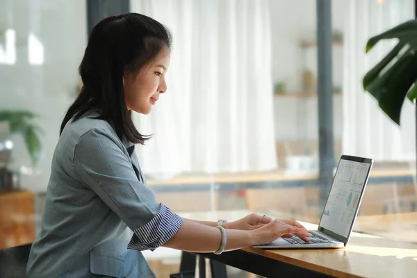 美しい若い女性が明るい現代のコーヒーショップに座って ラップトップコンピュータでオンラインで働いています — ストック写真