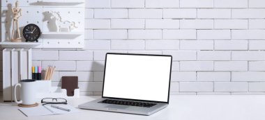 Dizüstü bilgisayarı, kitapları, kahve fincanı ve bitkisi olan şık bir çalışma masası..