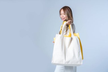 Beyaz arka planda duran boş tuval çantası taşıyan çekici bir kadın. Çevre dostu yaşam tarzı.. 