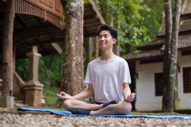 Nilüfer çiçeğinin üzerinde oturup meditasyon yapan barışçıl bir adam. Yoga, pilates, spor, sağlıklı yaşam tarzı konsepti.