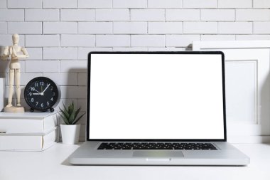 Boş ekran, kitaplar, çalar saat ve beyaz masaya konmuş saksı bitkisi olan ön görünüm dizüstü bilgisayarı.