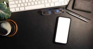 Düz kontak cep telefonu, bardaklar, kahve fincanı ve malzemeler siyah masada..