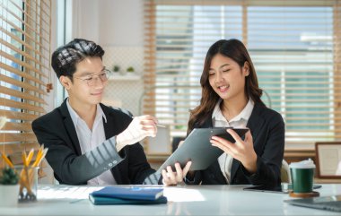 İki genç iş arkadaşı mali verileri tartışıyor, parlak iş yerinde birlikte çalışıyorlar..