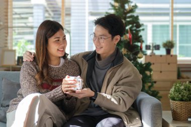 Sıcak çikolata içen, Noel tatilini birlikte kutlayan genç çifti seviyorum..