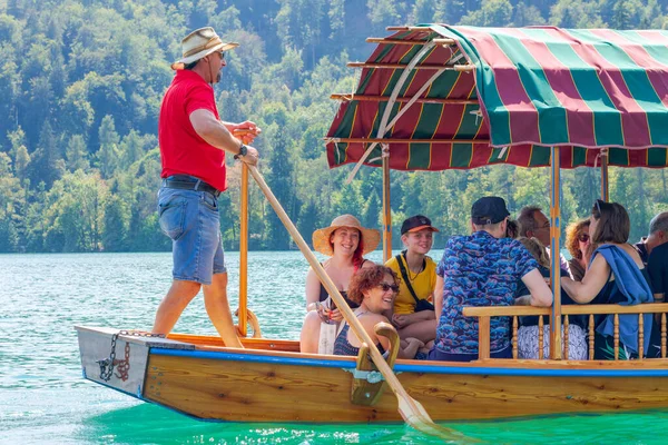 Lake Bled, Slovenia - August 20, 2018: A rower talks to tourists while driving them around in a traditional 'pletna' wooden boat