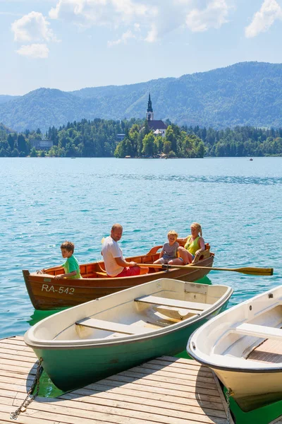 Lake Bled, Slovenia - August 20, 2018: A family approaches the pier while enjoying the water and landscape on a row boat in summer.