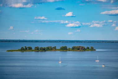 Ukrayna 'daki Dinyeper nehrinde bir ada. Adaya üç yat yaklaşıyor. Renkli yaz manzarası.