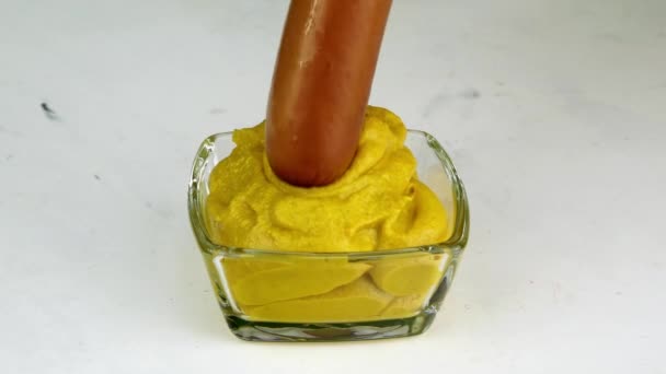 Salsicha mergulhada em mostarda, que fica em tigela de vidro, para comer. Fast saborosa comida caseira picante. — Vídeo de Stock