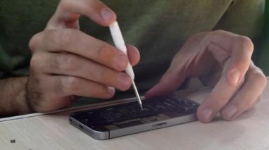 Kiev, Ukrayna, Temmuz 2021 telefon tamircisi akıllı telefonu tornavidayla tamir ediyor. Tadilattan sonra hizmet merkezindeki işyerinde elektronik ekipman topluyor. Eller yakın çekim. Kapalı.