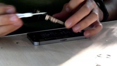 Kiev, Ukrayna, Temmuz 2021 telefon tamircisi akıllı telefonu tornavidayla tamir ediyor. Tadilattan sonra hizmet merkezindeki işyerinde elektronik ekipman topluyor. Eller yakın çekim. Kapalı.