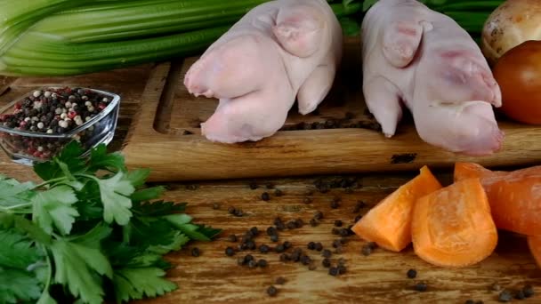 生の豚肉の足、木製のキッチンボード上のおいしい在庫やスパイスを準備するための異なる野菜やスパイス。ドリーショット. — ストック動画