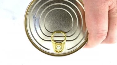 El, metal konserve sardalya ya da uskumru konservesini sebze yağında açar. Metal kapağı kaldırıyor. Sağlıklı konserve yiyecek konsepti. Üst görünüm.