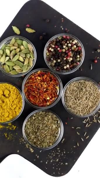 Různé indické koření a byliny rotoval na bílém pozadí ve skleněných miskách. — Stock video