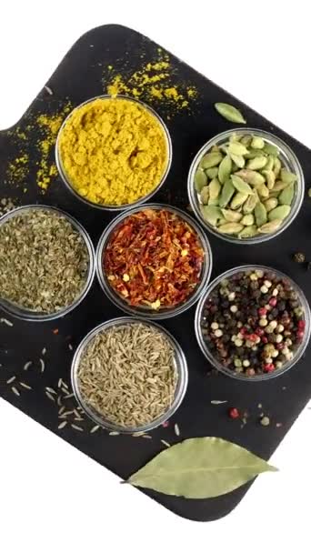 Różne indyjskie przyprawy i zioła obracane na białym tle w szklanych miskach. — Wideo stockowe