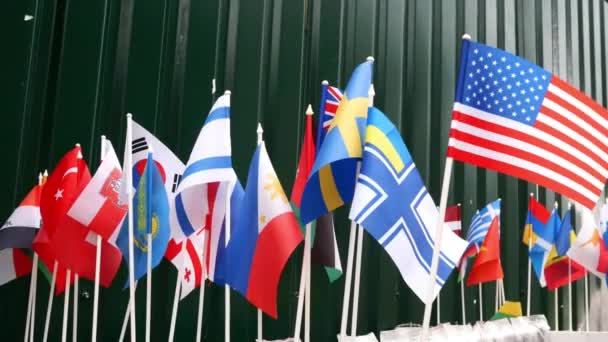 Pequeñas banderas nacionales de diferentes países balanceándose sobre viento ligero en el mostrador en el mercado callejero. — Vídeo de stock
