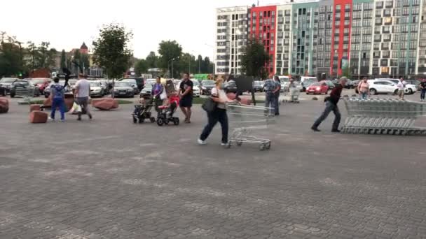 Kiev, Ucrania, agosto de 2021: - Personas que usan máscaras con carritos de compras que entran o salen del supermercado. Coches en el aparcamiento. — Vídeos de Stock