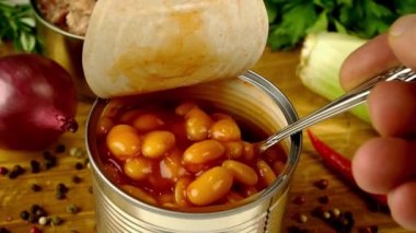 Şef, ahşap mutfak tahtasındaki metal teneke kutudan domates soslu kaşık fasulyeyle alır..