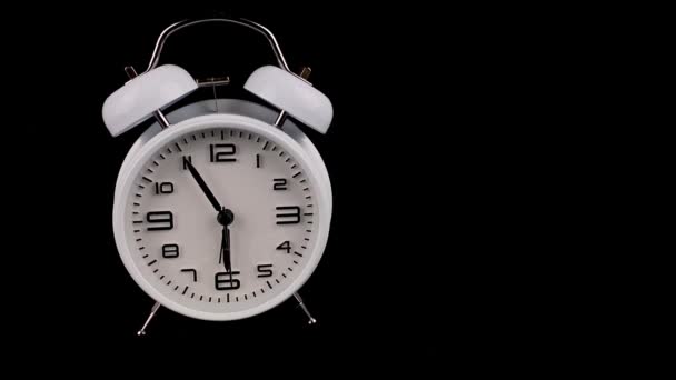 Old fashioned white alarm clock stands on black background and rings at 6 six oclock, in morning. — ストック動画