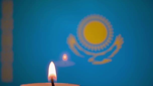 Kiev, Ukraine, January 2022: - Memorial single burning candle in front of background of blurred Kazakh flag. Selective focus. Focus on candle. — Wideo stockowe