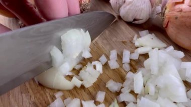 Chef hands chop finely raw onion on wooden cutting board with kitchen knife. Slow motion.