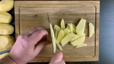 Chef hands cut raw potato into strip on wooden cutting board with kitchen knife. Time lapse.