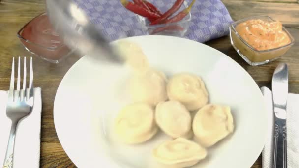 Meat dumplings or ravioli put in white bowl and pour with melted butter. Close-up. — Stock Video