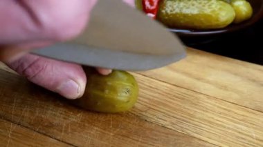 Salatalık turşusu ahşap mutfak tahtasını keskin bir bıçakla kesiyor..