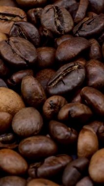 Kokulu kavrulmuş koyu kahve çekirdekleri orta pişmiş kahve çekirdekleri dairesel rotasyon. Üst Manzara. Dikey. Yakın plan..