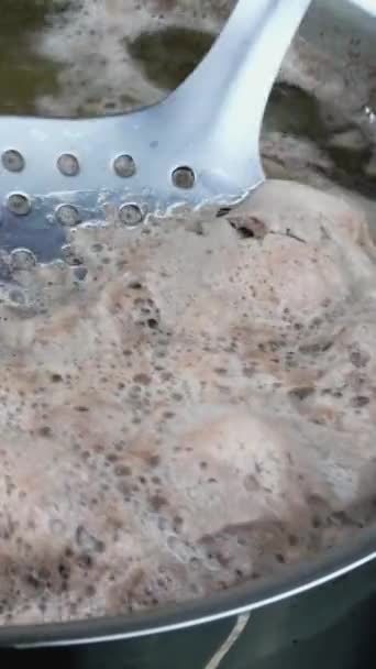 М'ясний бульйон з великою кількістю піни кипить у каструлі, піну видаляють металевою щілинною ложкою . — стокове відео