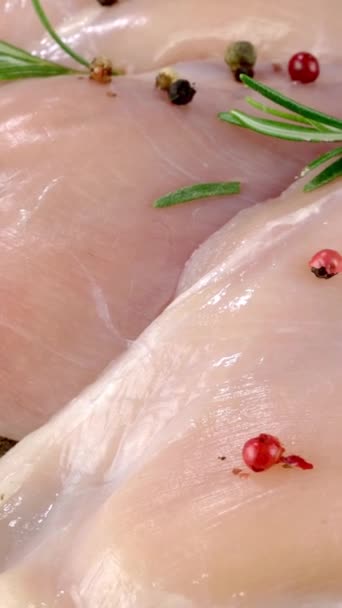 Čerstvé syrové kuřecí prsní filety posypané pepřem a rozmarýnem se pomalu otáčí. — Stock video