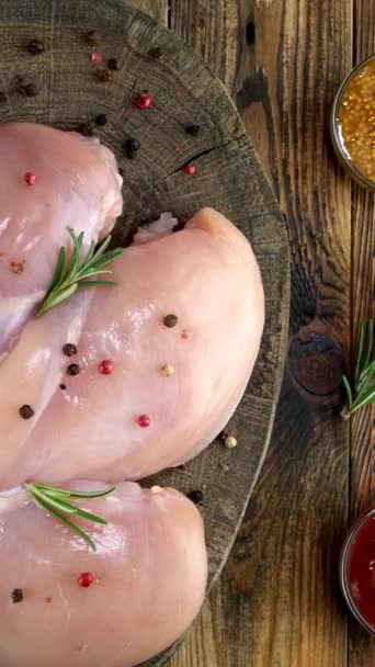 Fresh raw chicken breast fillets sprinkled with peppercorns, rosemary, sauces rotates slowly. — Stock Video
