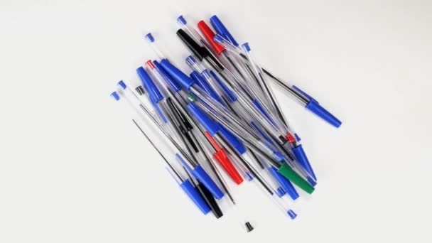 Beaucoup de stylos à bille colorés tournent lentement sur écran blanc au bureau ou à l'école. — Video