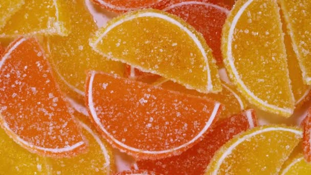Sabrosa mermelada de naranja gomosa jalea de frutas, espolvoreada con caramelos de azúcar, rotar lentamente. — Vídeos de Stock