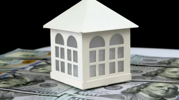 Modelo de pequeña casa familiar de pie sobre fondo de billetes de dólares y rotar lentamente. — Vídeos de Stock