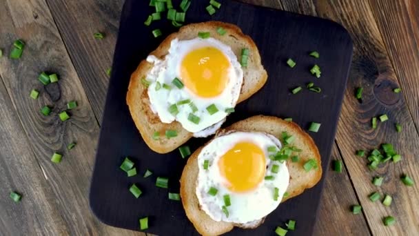 Сэндвич с яичницей и желтком на поджаренном куске хлеба, посыпанном зеленым луком. — стоковое видео