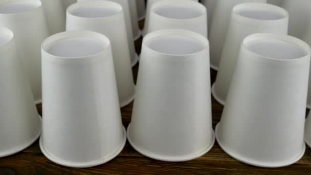 Row of white disposable paper cup for coffee or hot beverage on dark backdrop rotate slowly. — Stock Video