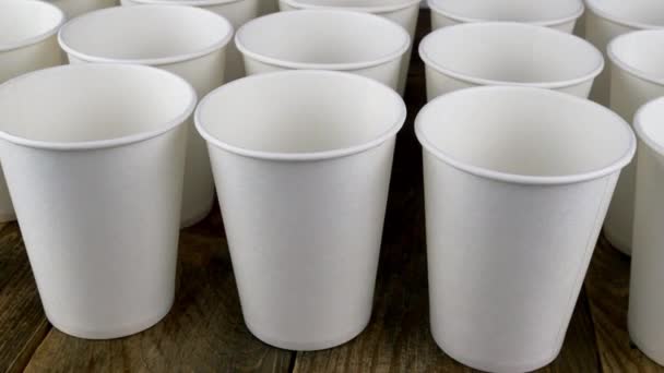 Ряд белого одноразового бумажного стаканчика для кофе или горячего напитка на темном фоне вращаются медленно. — стоковое видео