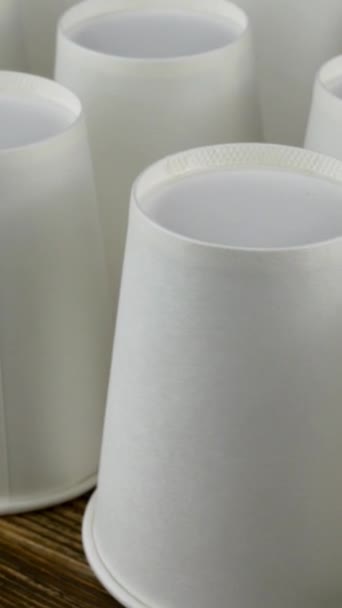 Row of white disposable paper cup for coffee or hot beverage on dark backdrop rotate slowly. — Stock Video